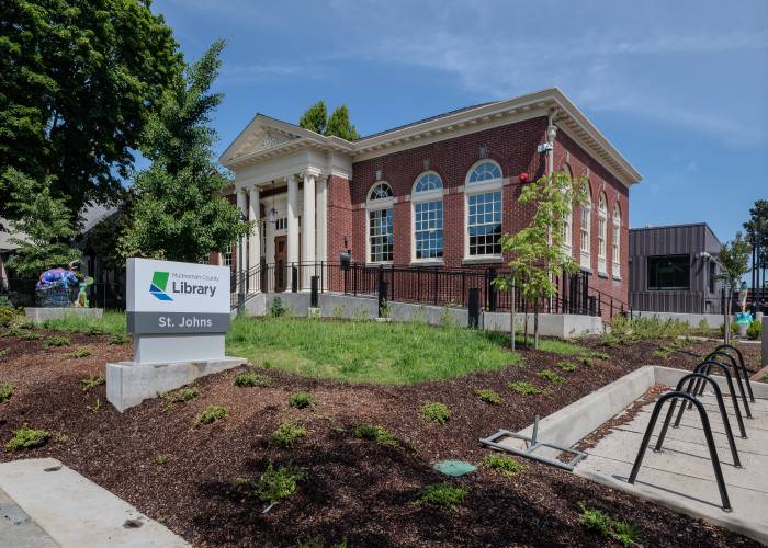 Exterior of the expanded St. Johns Library with plants and sculptures, links to more information about St. Johns Library opening. 