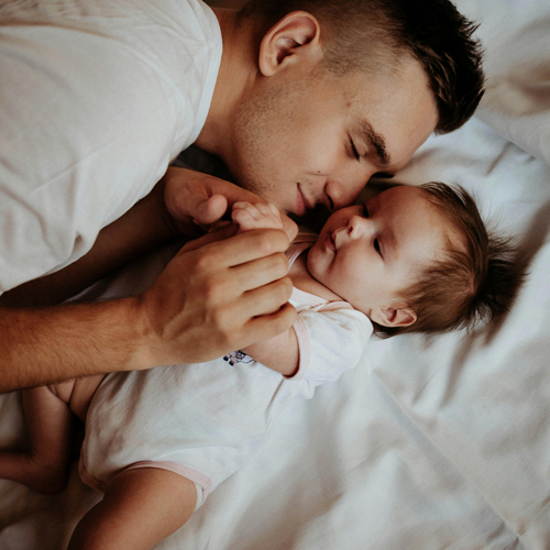 A father snuggles with his young baby, links to information on self regulation for babies and toddlers.
