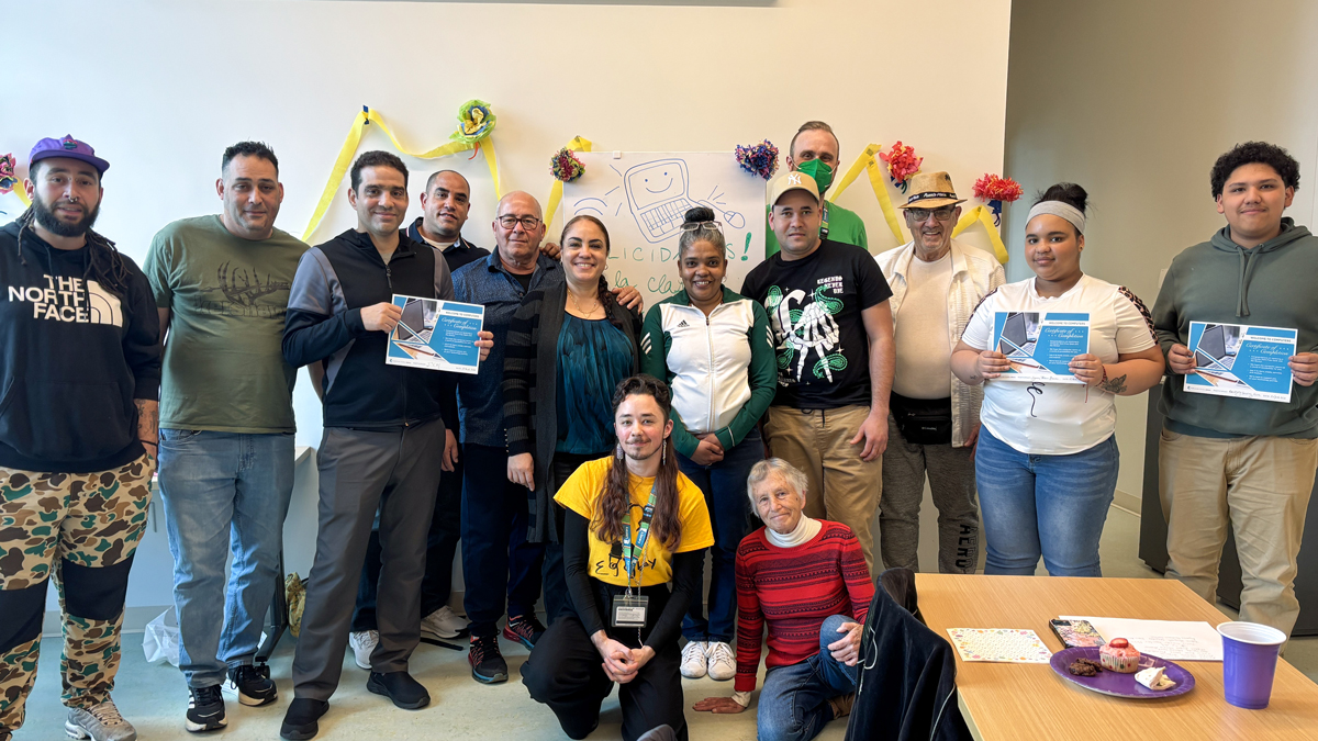 A group of 14 people from a Welcome to Computers Class holding certificates and smiling.